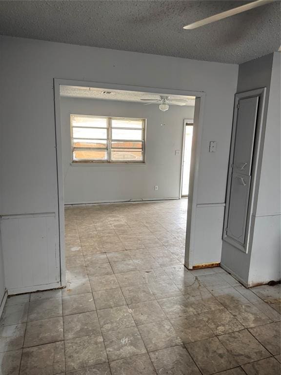 spare room featuring baseboards, a textured ceiling, and ceiling fan