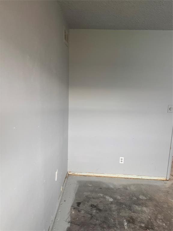 unfurnished room featuring a textured ceiling and unfinished concrete flooring