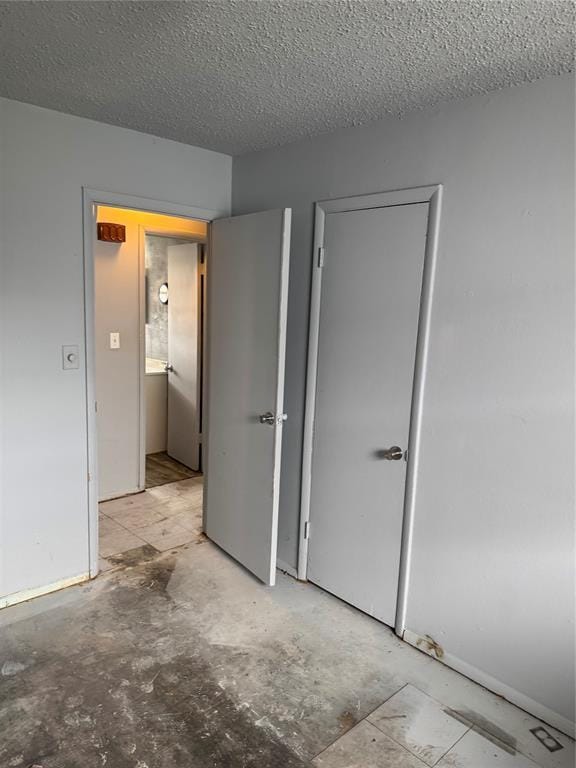 unfurnished bedroom featuring a closet, concrete floors, and a textured ceiling