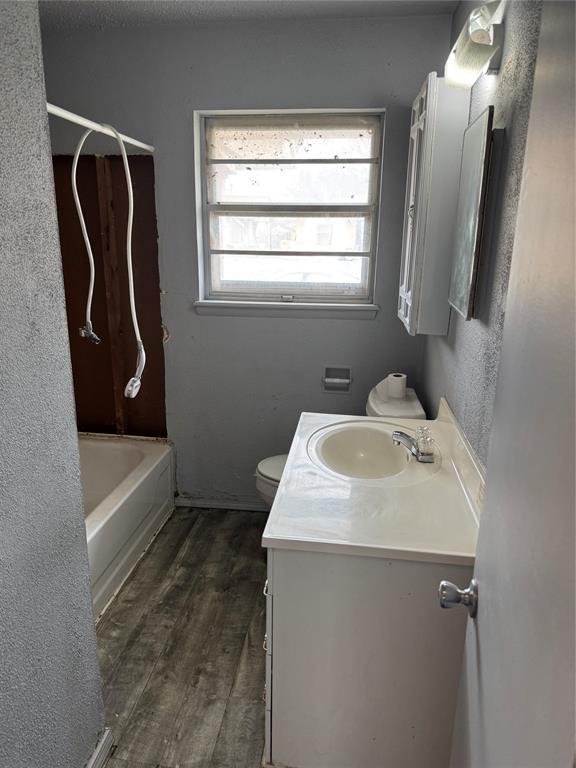 bathroom with toilet, tub / shower combination, vanity, and wood finished floors