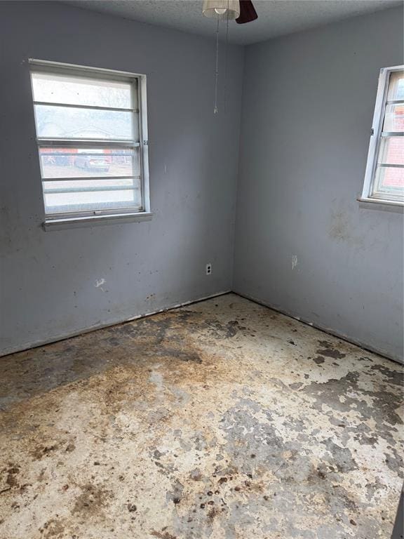 unfurnished room with ceiling fan and a textured ceiling