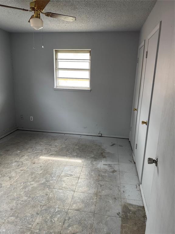 empty room featuring a textured ceiling and a ceiling fan