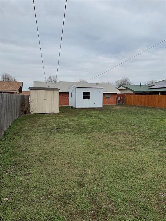 view of yard featuring an outbuilding, a storage unit, and a fenced backyard