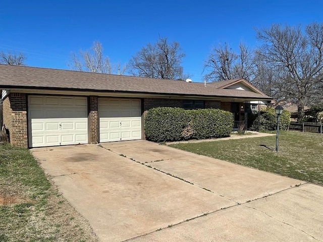 single story home with driveway, roof with shingles, a front yard, an attached garage, and brick siding