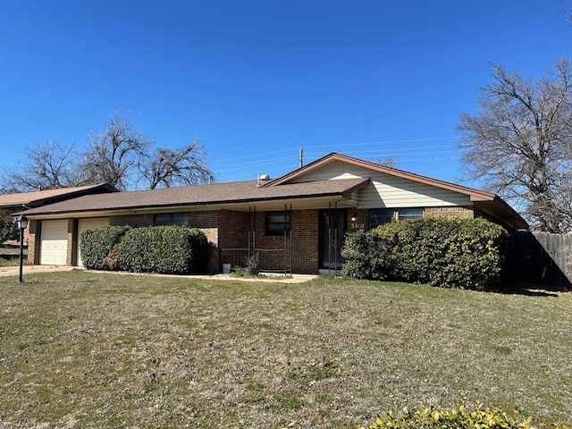 view of front of home with a front yard, brick siding, an attached garage, and fence