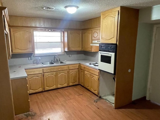 kitchen with light wood-style flooring, light brown cabinetry, a sink, under cabinet range hood, and white appliances