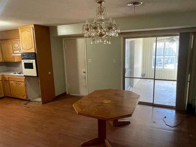 dining room with a notable chandelier, visible vents, light wood finished floors, and a textured ceiling