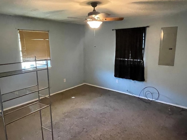 carpeted spare room featuring electric panel, ceiling fan, and baseboards