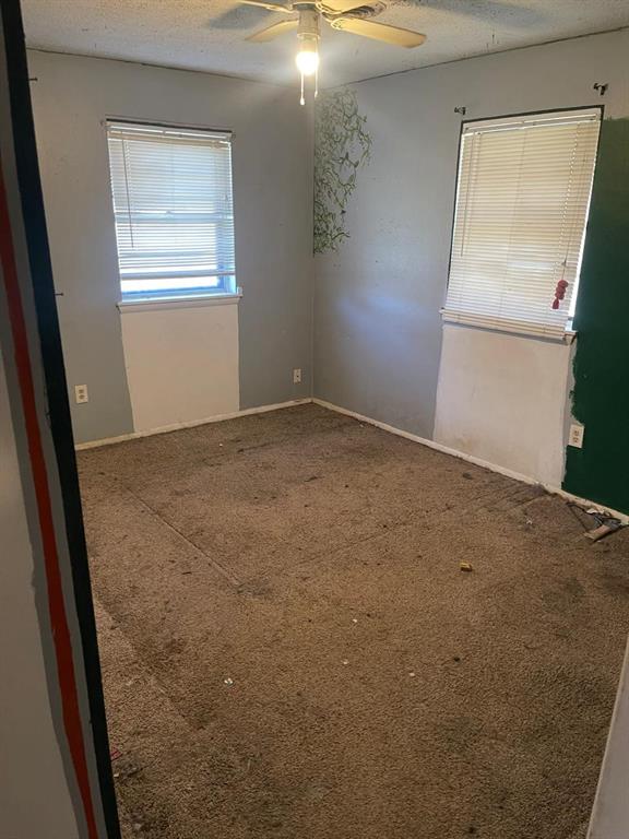 carpeted empty room featuring baseboards, a textured ceiling, and ceiling fan