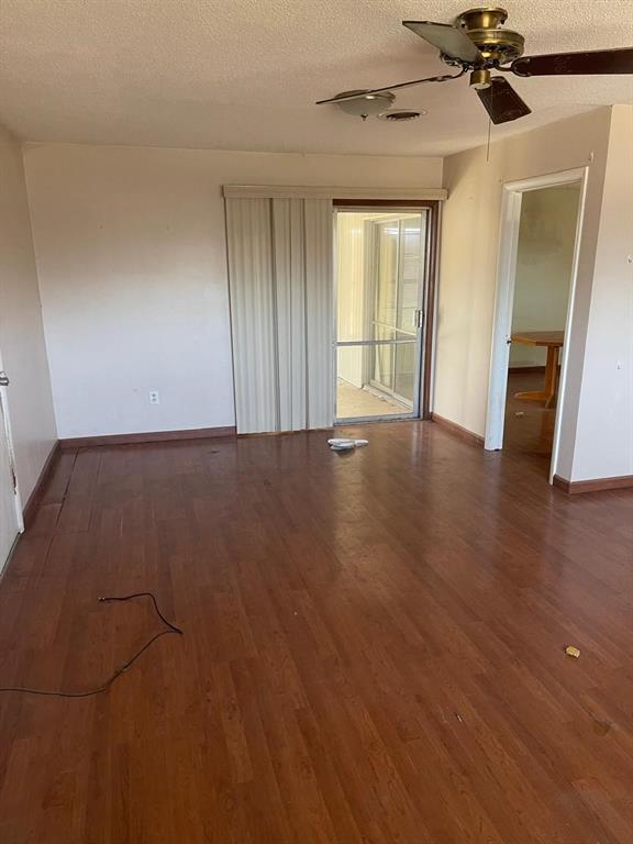 spare room featuring visible vents, baseboards, ceiling fan, wood finished floors, and a textured ceiling