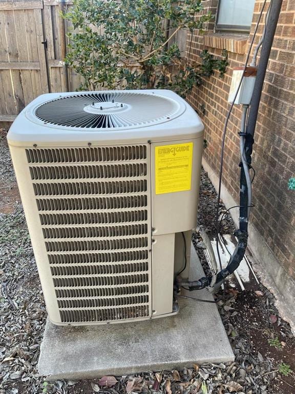 exterior details with central air condition unit, brick siding, and fence