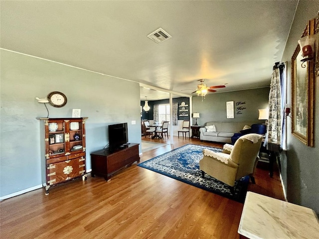 living area featuring ceiling fan, visible vents, and wood finished floors