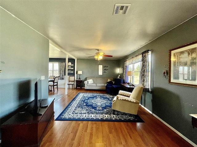 living area featuring plenty of natural light, wood finished floors, visible vents, and ceiling fan