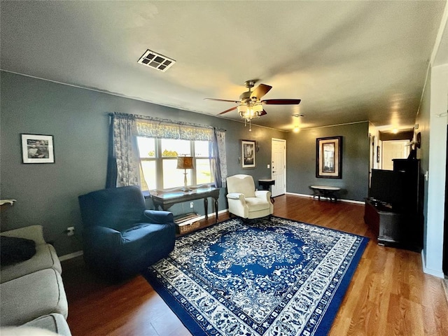 living area featuring visible vents, baseboards, ceiling fan, and wood finished floors