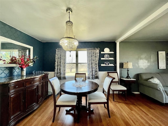 dining area with a chandelier, wood finished floors, and wallpapered walls