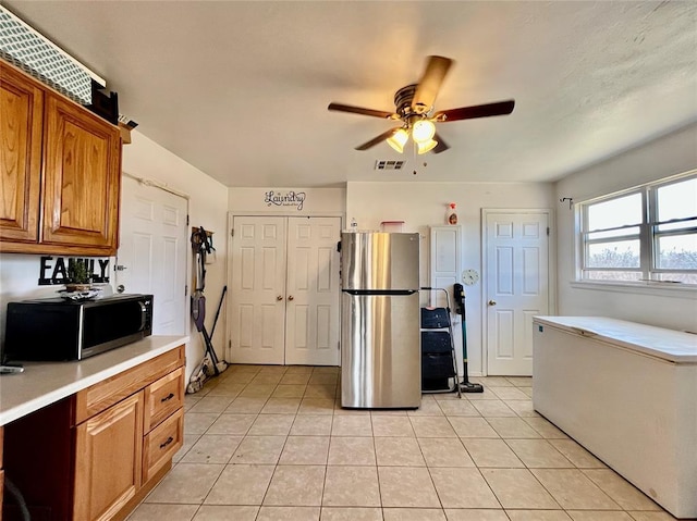 kitchen featuring visible vents, light countertops, light tile patterned floors, brown cabinetry, and stainless steel appliances