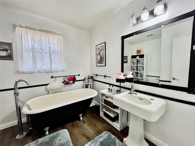 bathroom featuring visible vents, baseboards, a soaking tub, and wood finished floors