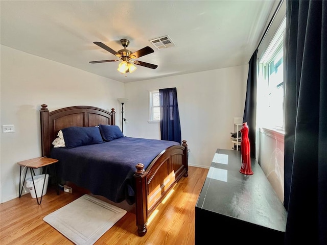 bedroom with visible vents, light wood-style floors, and a ceiling fan