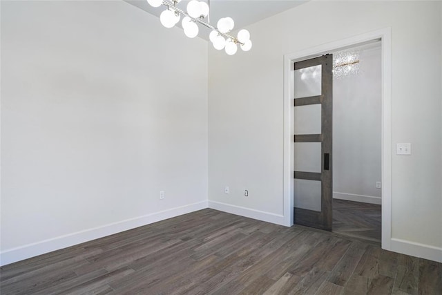 unfurnished room with dark wood-type flooring, baseboards, and a chandelier