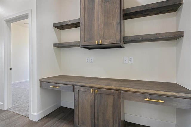 interior space with baseboards, dark wood-style floors, and built in desk