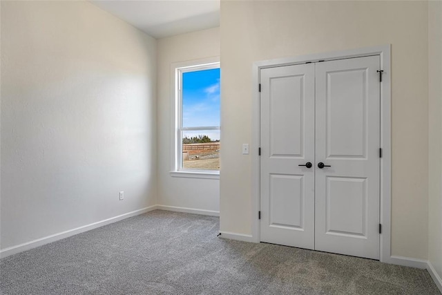 unfurnished bedroom with baseboards, carpet floors, and a closet