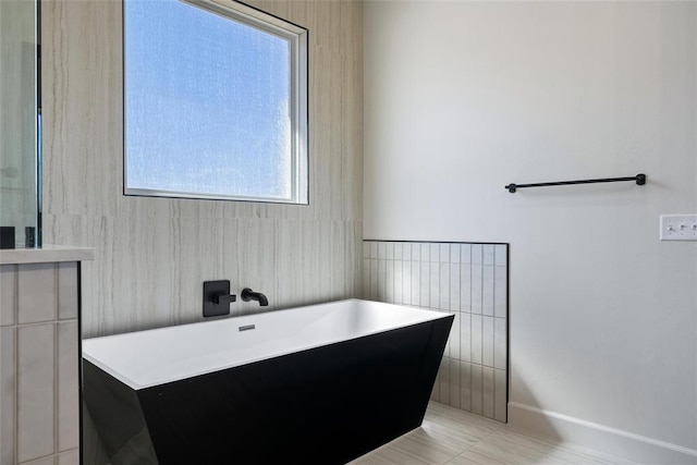 full bathroom with a soaking tub and tile walls