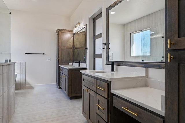 full bathroom with two vanities, baseboards, and a sink