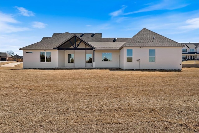 back of property with a yard and a shingled roof