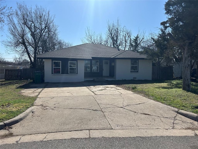 ranch-style home with driveway, a shingled roof, a front lawn, and fence