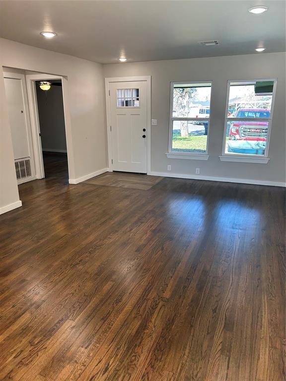 foyer entrance featuring dark wood-style floors, visible vents, and baseboards