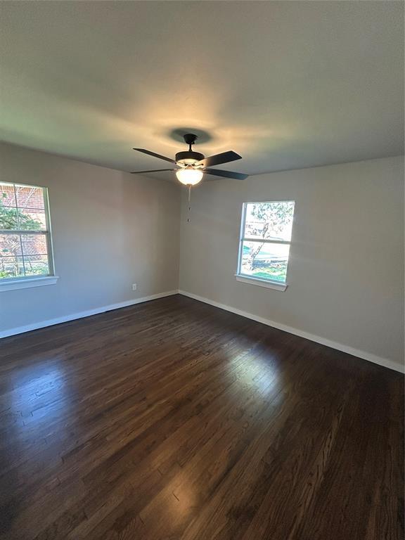 unfurnished room featuring a ceiling fan, dark wood-style floors, a healthy amount of sunlight, and baseboards