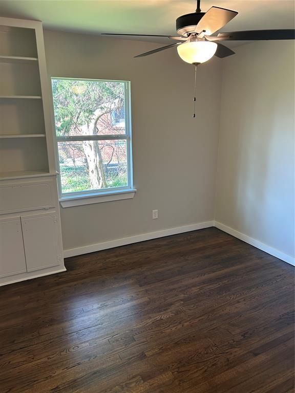 spare room with a ceiling fan, dark wood-style floors, and baseboards