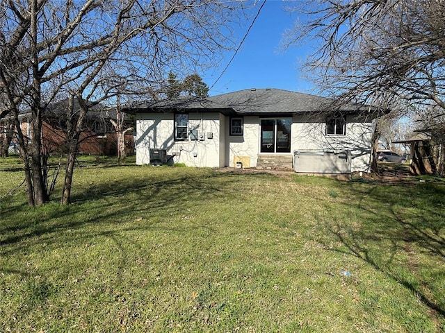 exterior space with central air condition unit, a yard, and roof with shingles