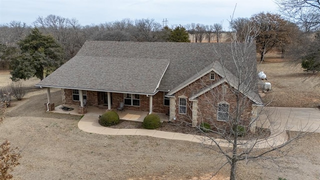 view of front of home with brick siding, a porch, and a shingled roof