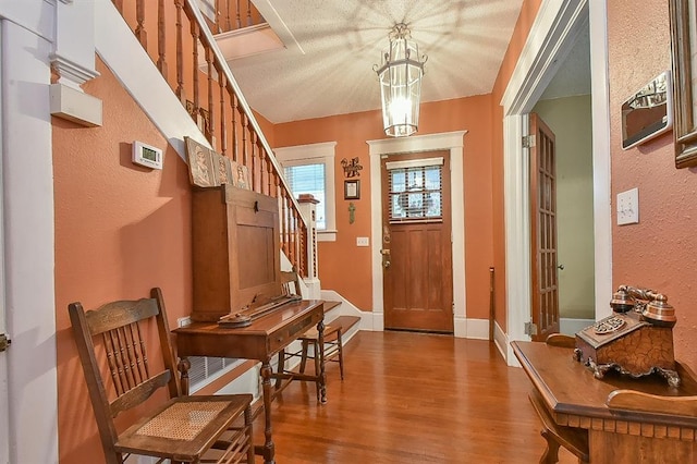 entrance foyer featuring a chandelier, stairs, baseboards, and wood finished floors