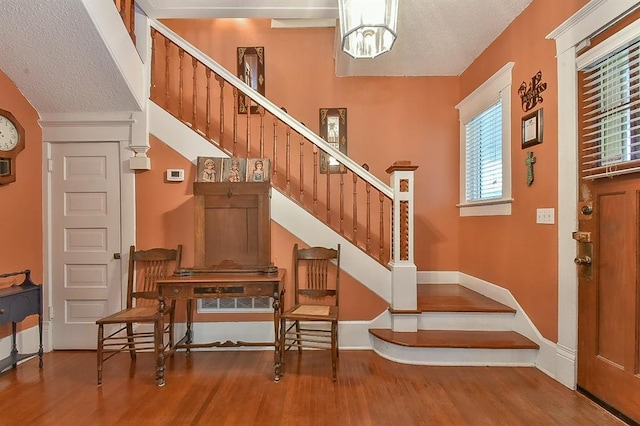 foyer entrance featuring a textured ceiling, stairs, and wood finished floors