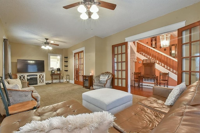 carpeted living room with stairway, a ceiling fan, baseboards, french doors, and a textured ceiling