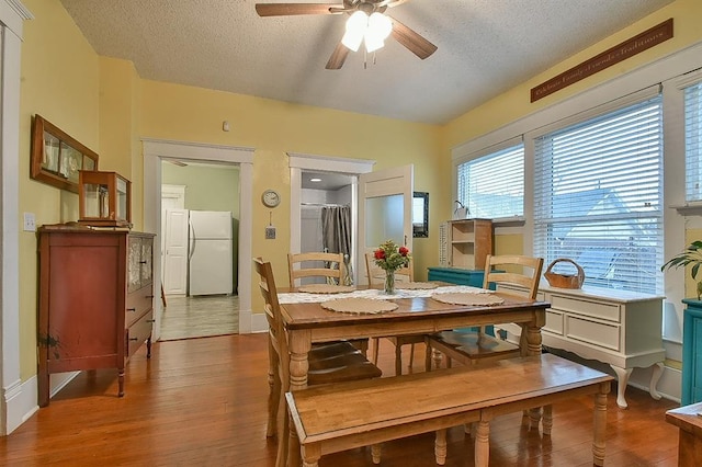 dining space with baseboards, a textured ceiling, wood finished floors, and a ceiling fan