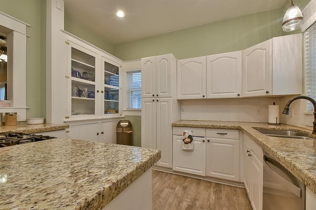 kitchen with tasteful backsplash, dishwasher, light wood-type flooring, white cabinets, and a sink