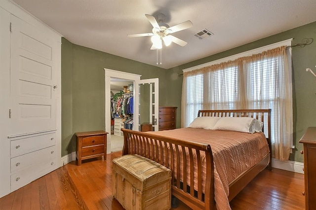 bedroom with hardwood / wood-style floors, baseboards, visible vents, a closet, and a walk in closet