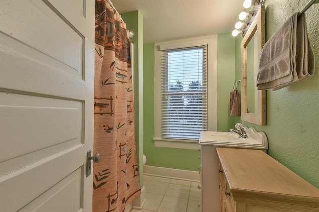 bathroom featuring vanity, tile patterned floors, a healthy amount of sunlight, and baseboards