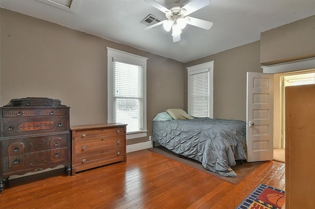 bedroom with a ceiling fan, hardwood / wood-style flooring, baseboards, and visible vents