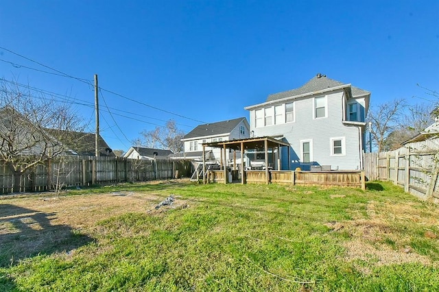 rear view of property featuring a lawn, a wooden deck, and a fenced backyard