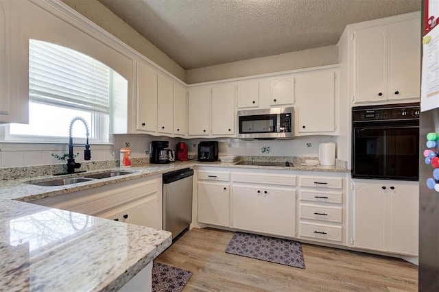 kitchen with a sink, black appliances, light wood-style floors, a textured ceiling, and white cabinetry