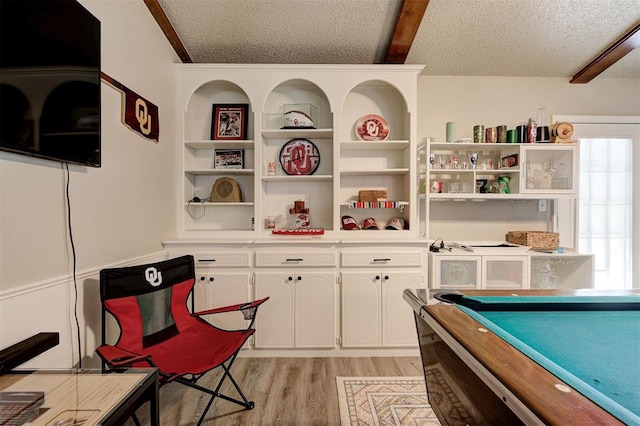 recreation room with light wood-style floors, a textured ceiling, beamed ceiling, and billiards