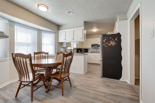 dining room featuring a textured ceiling, visible vents, and light wood-type flooring