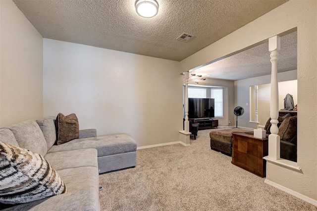 carpeted living room with ornate columns, visible vents, a textured ceiling, and baseboards
