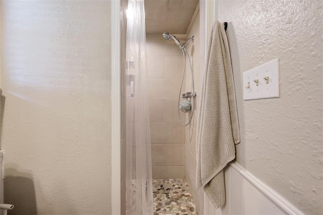 full bathroom with a textured wall and a tile shower