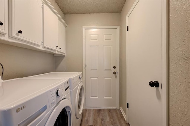 washroom with washing machine and dryer, light wood-style flooring, a textured wall, cabinet space, and a textured ceiling