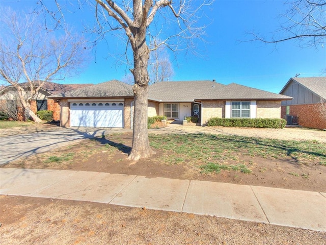 ranch-style house featuring central AC, an attached garage, brick siding, and driveway